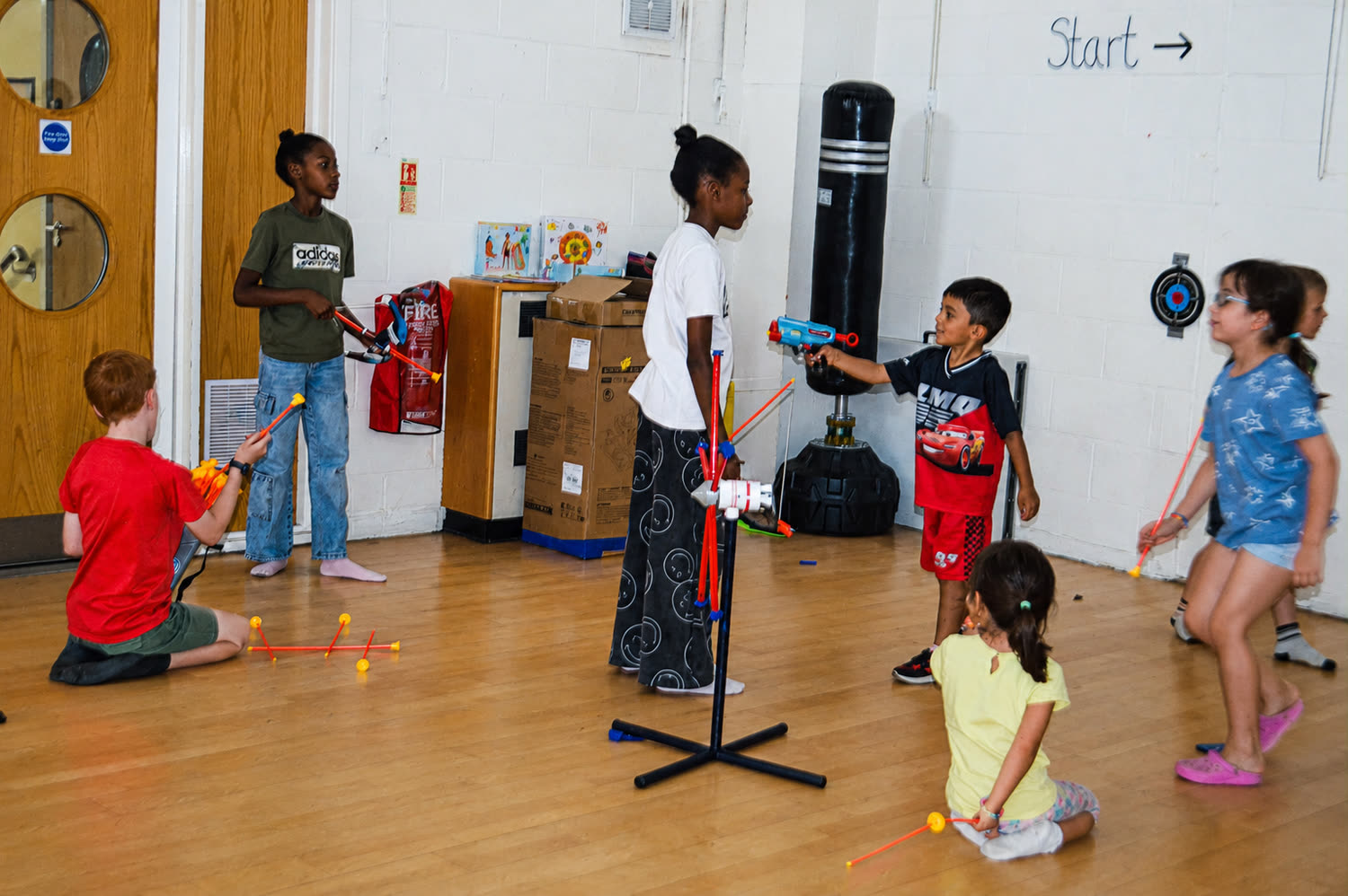 Children playing a target game in the hall, aiming foam darts at a target